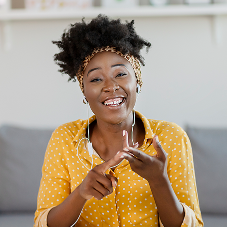 Frau mit Kopfh�rern schaut in die Kamera und z�hlt an den Fingern ab